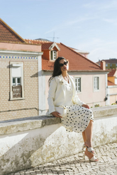a lady in a white blazer, a white vest and a white skirt with black polka dots